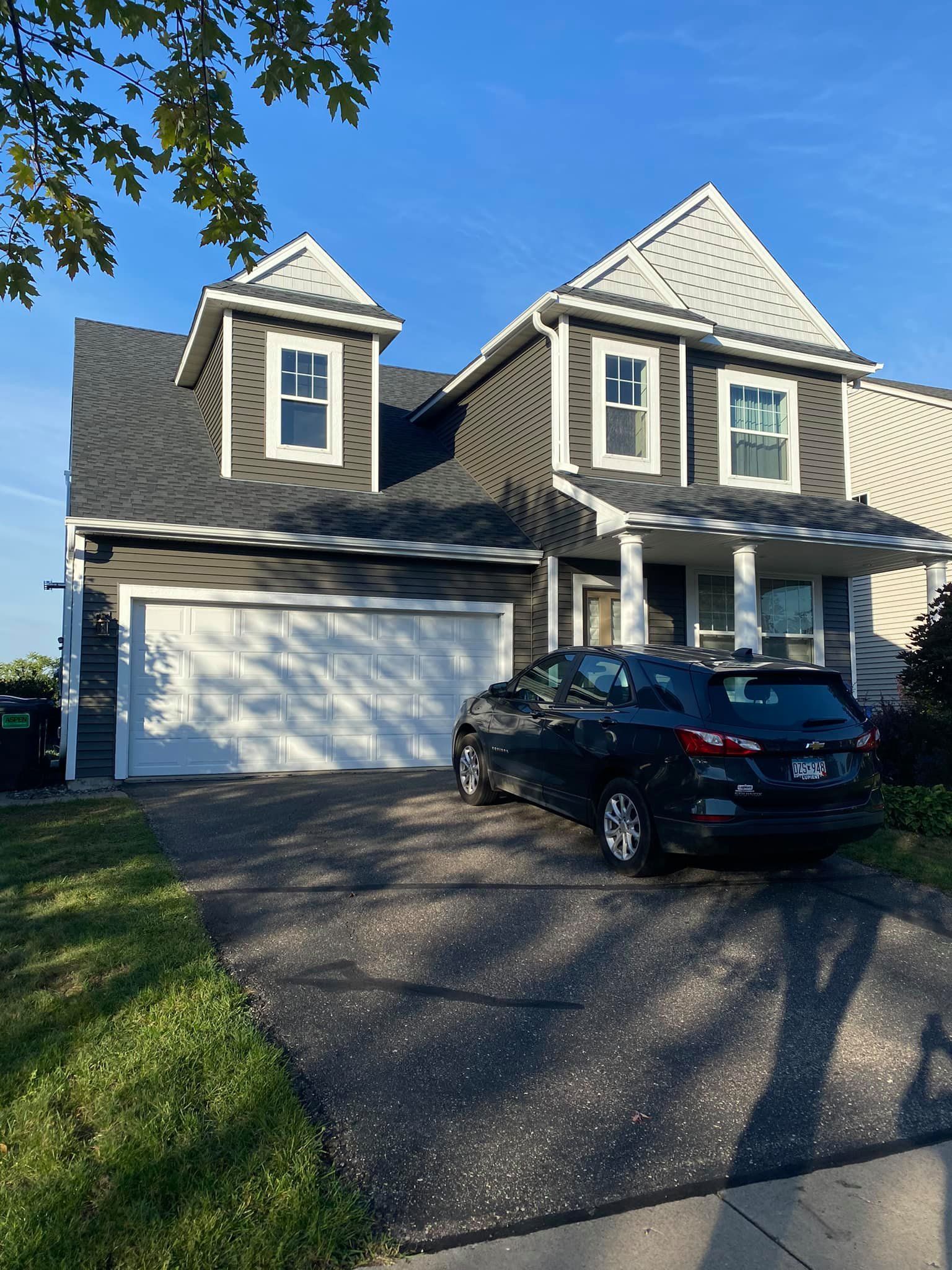 A black car is parked in front of a large house.