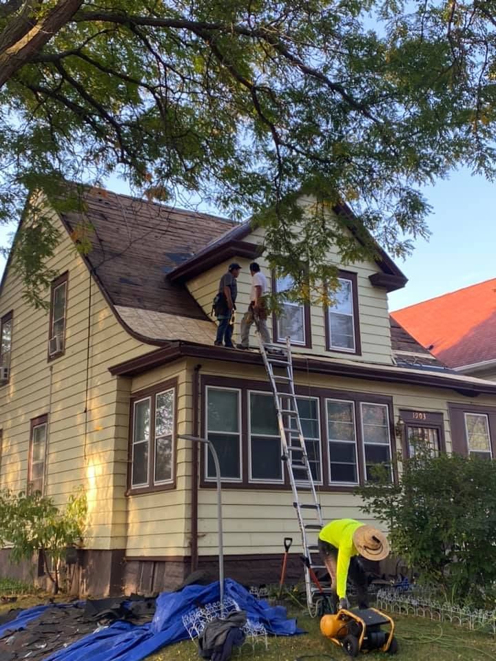 Two men are working on the roof of a house.