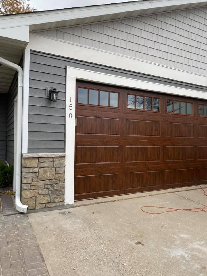 A brown garage door is on the side of a house.