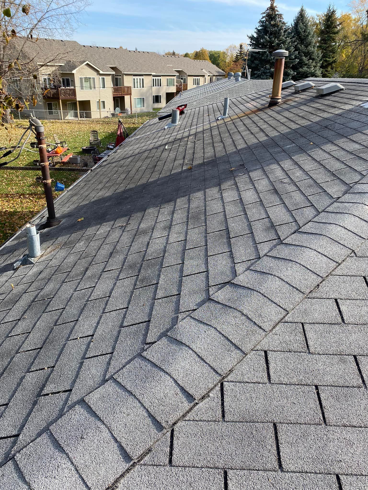 A roof with a lot of shingles on it and a building in the background.
