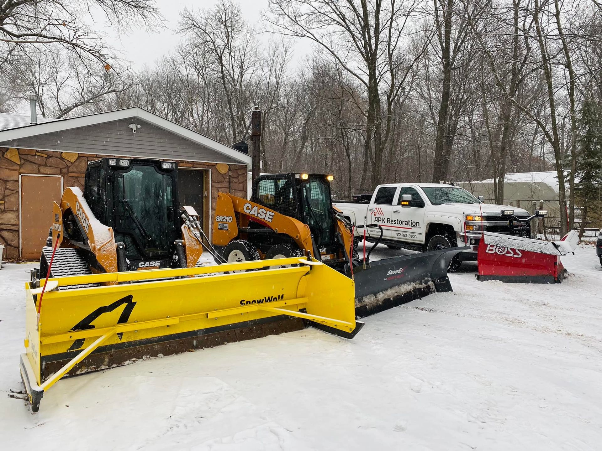 A couple of snow plows are parked in front of a house.