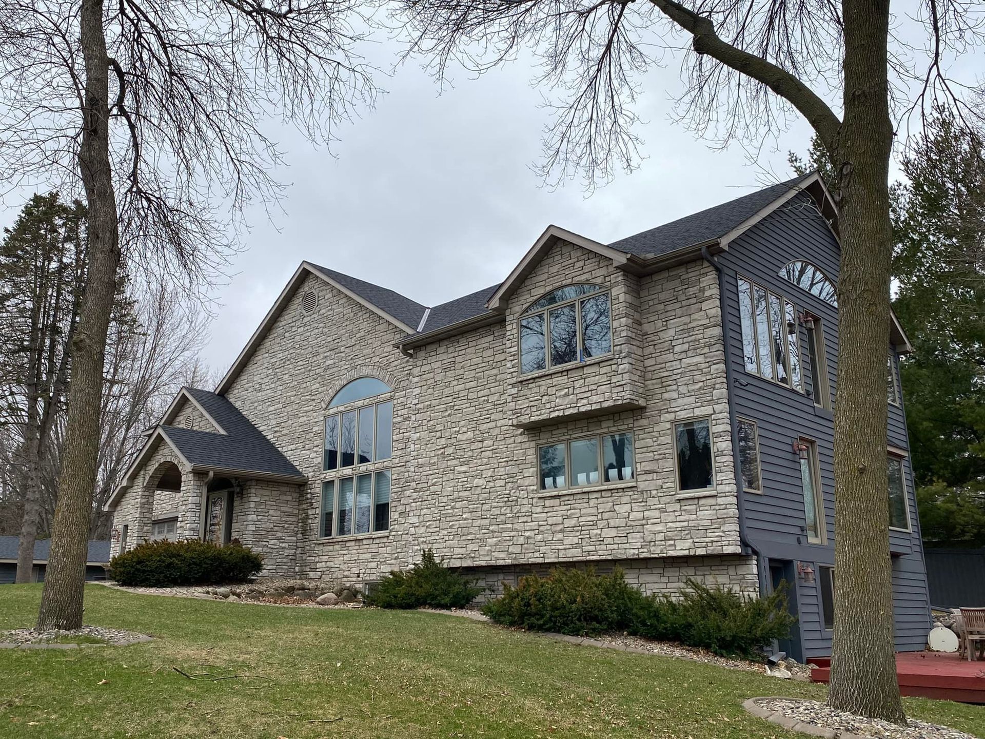 A large house with a lot of windows is sitting on top of a lush green hill.