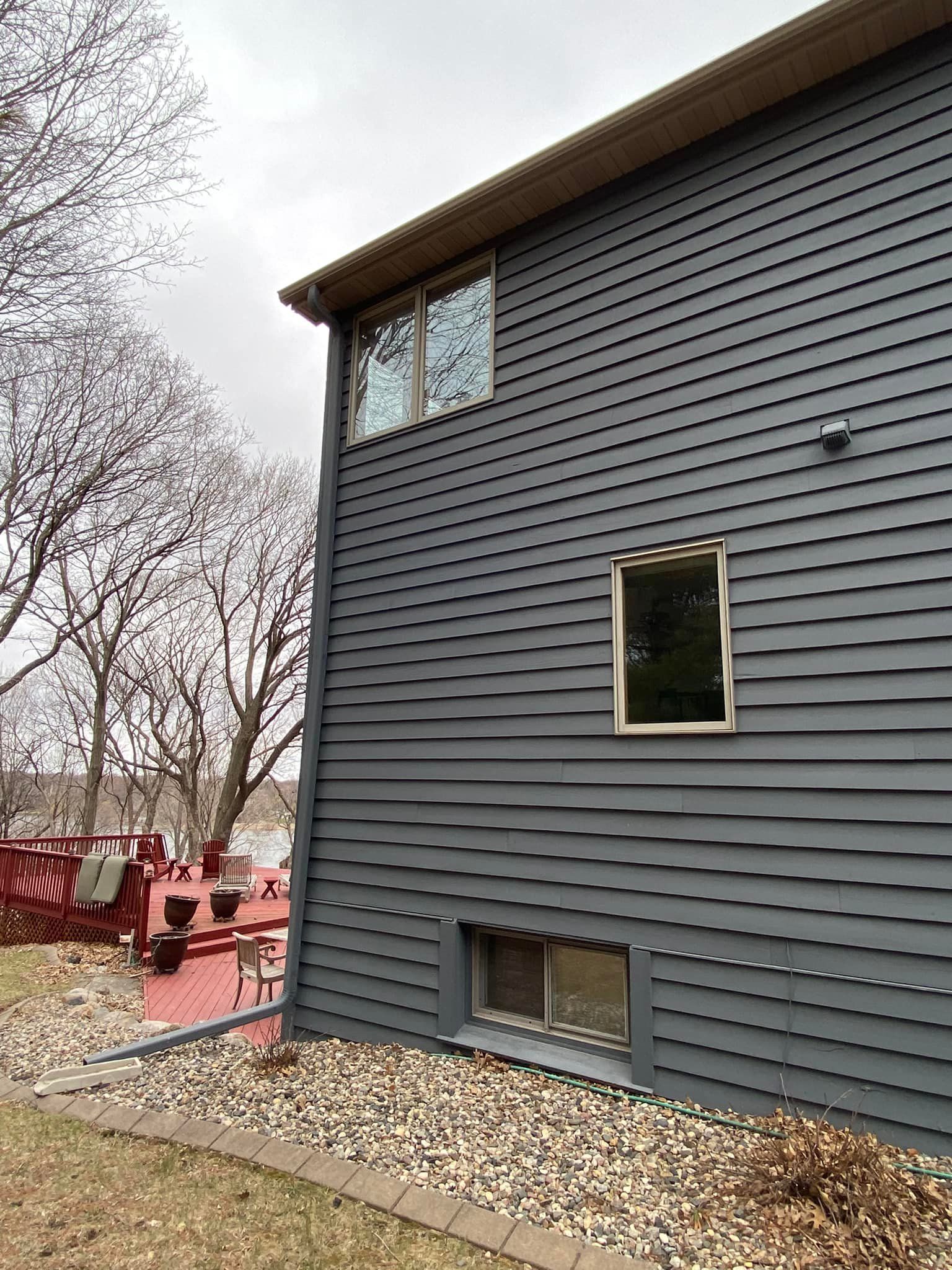 The side of a house with a lot of windows and a red deck.