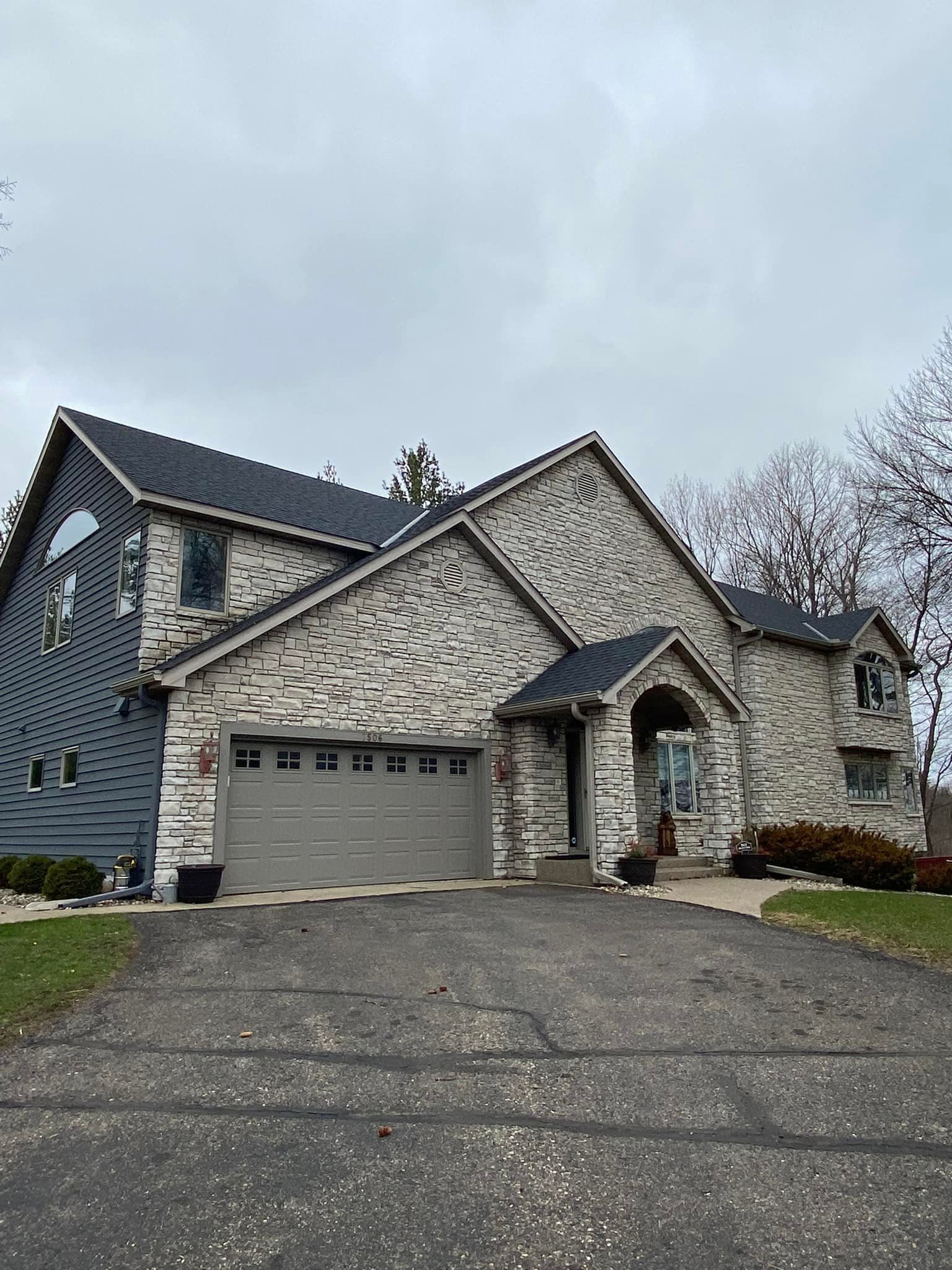 A large stone house with a garage and a driveway.