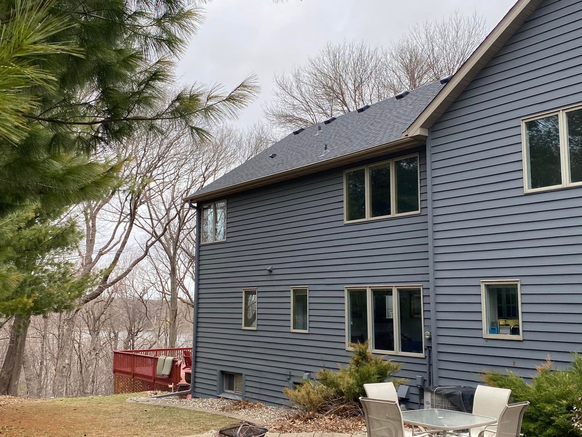 A large blue house with a lot of windows and a table and chairs in front of it.