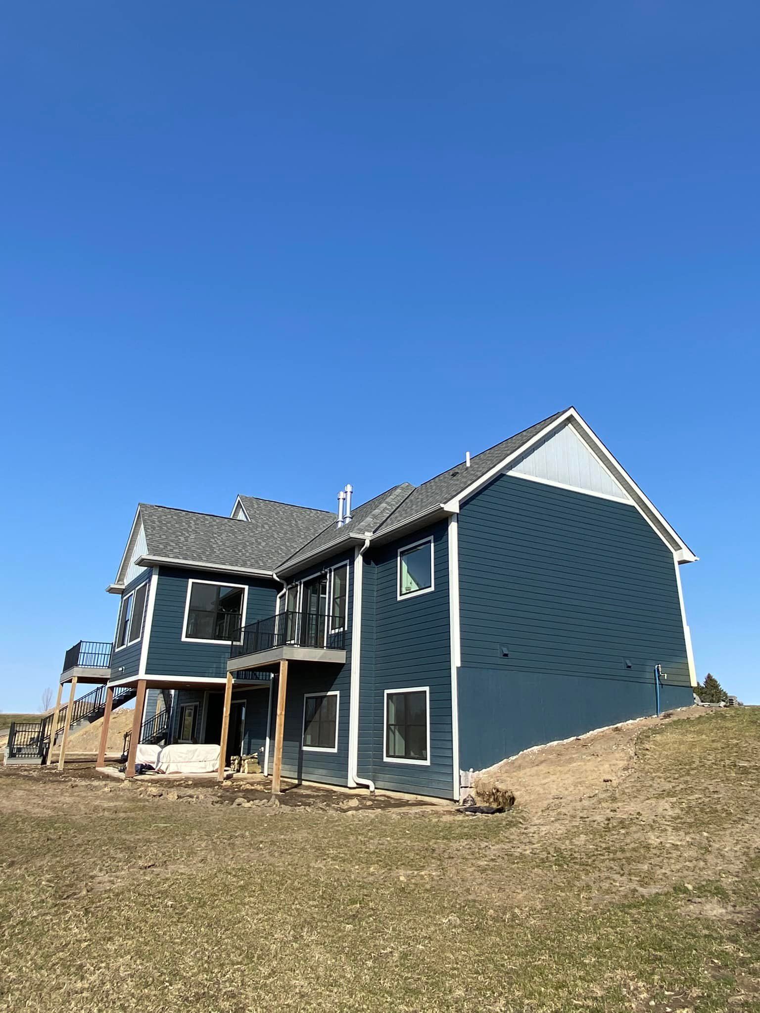 A large blue house is sitting on top of a grassy hill.
