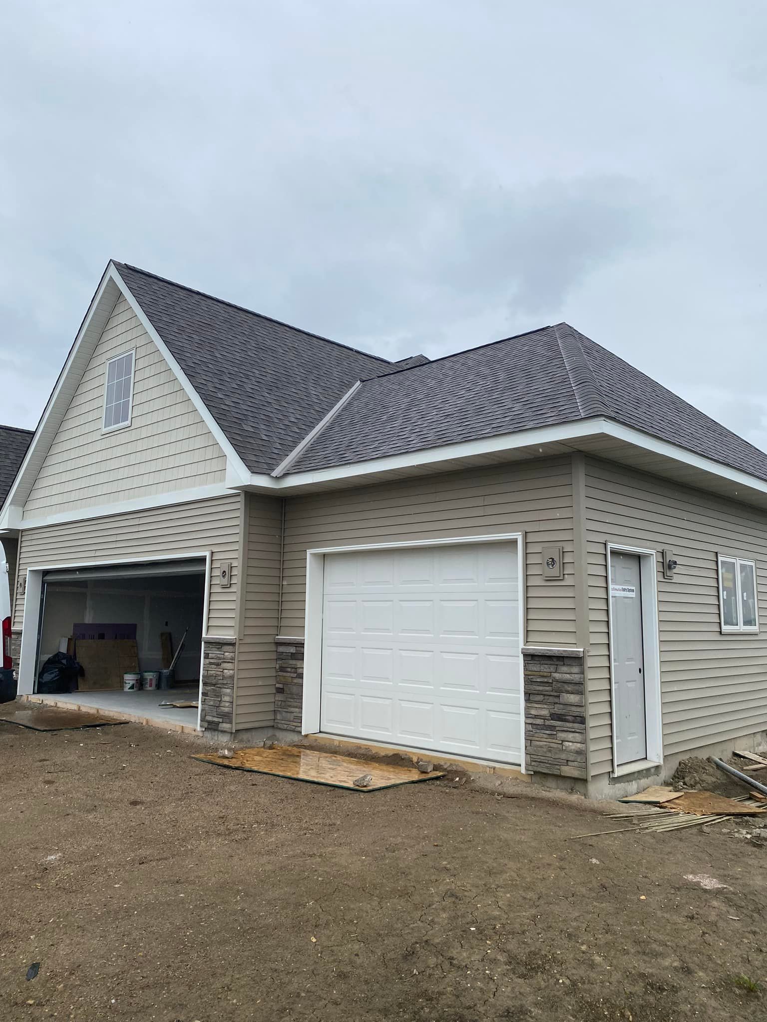A house with two garage doors and a gray roof is being built.