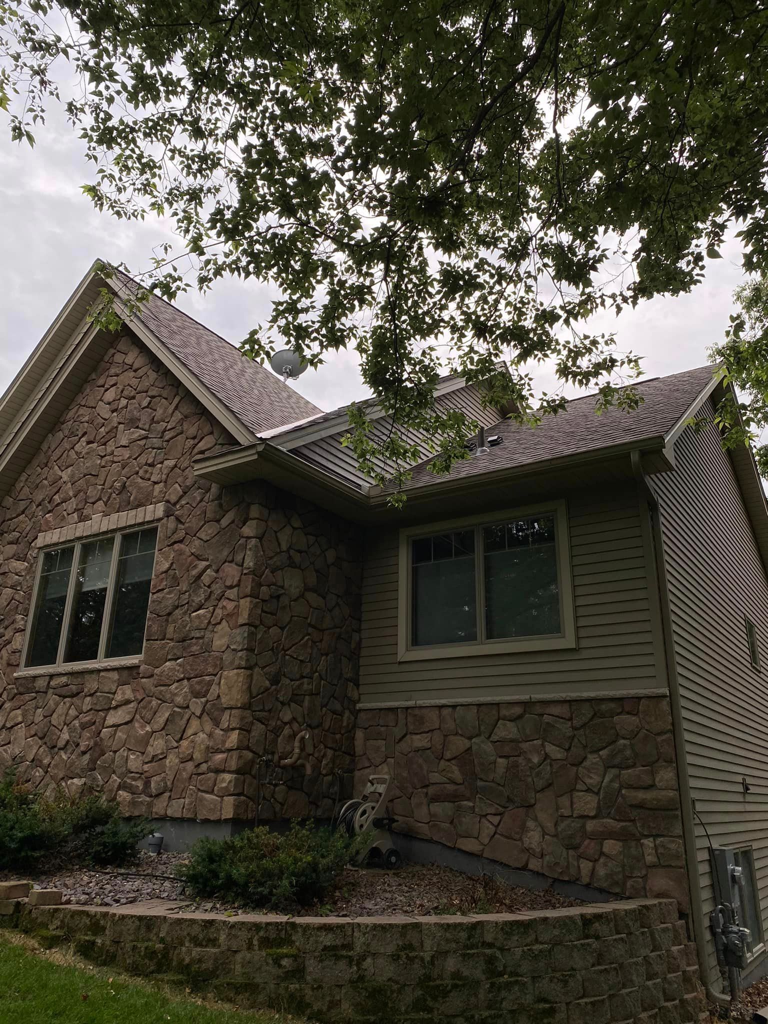 A brick house with a tree in front of it and a roof.