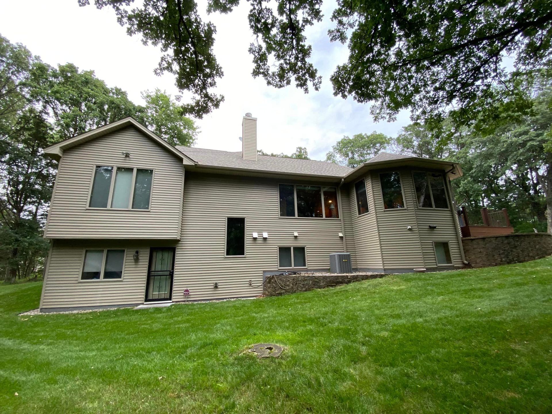 A large house is sitting on top of a lush green hillside surrounded by trees.