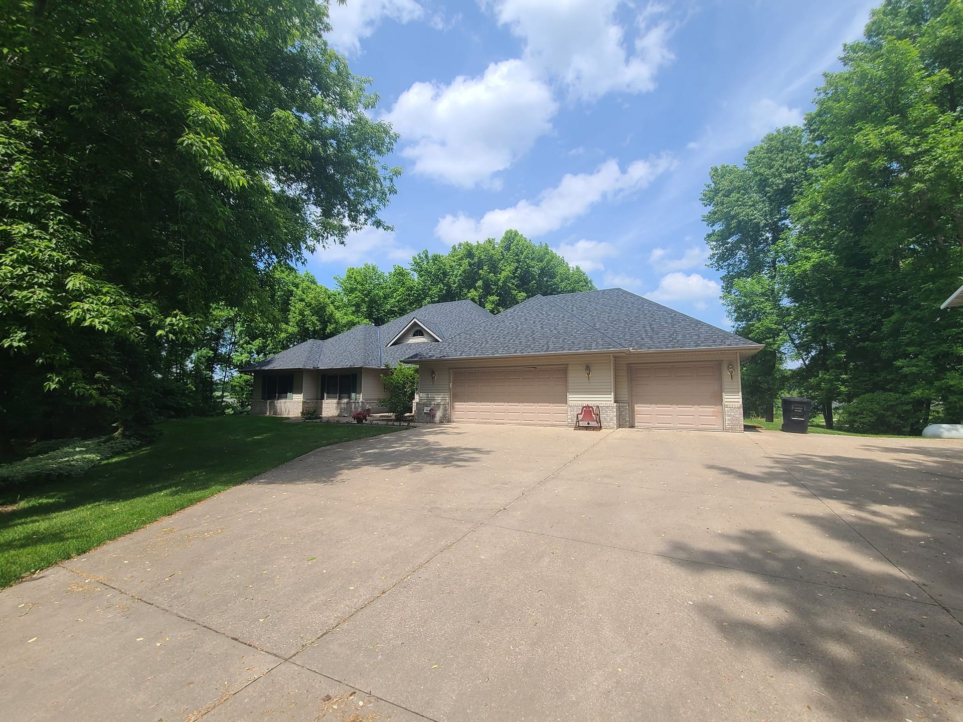 A large house with a large driveway and trees in front of it.