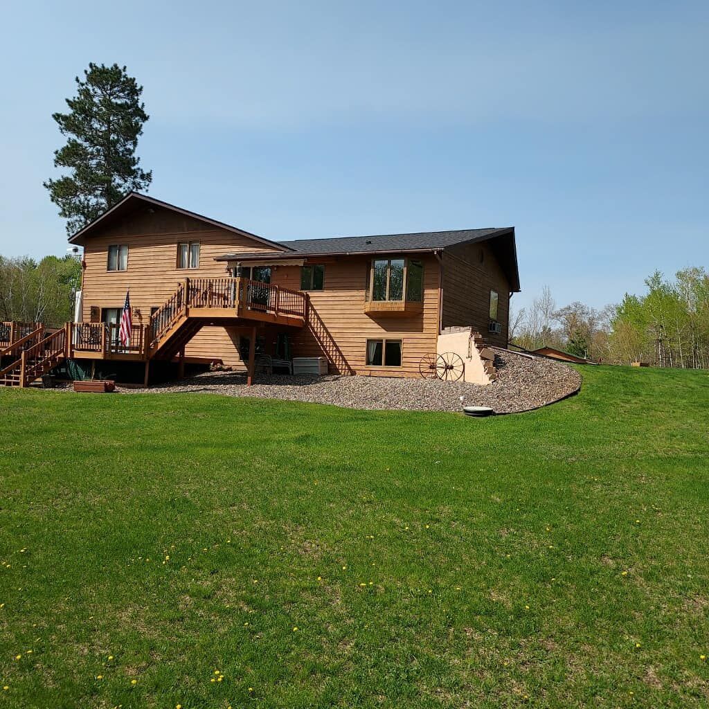 A large wooden house with a large lawn in front of it