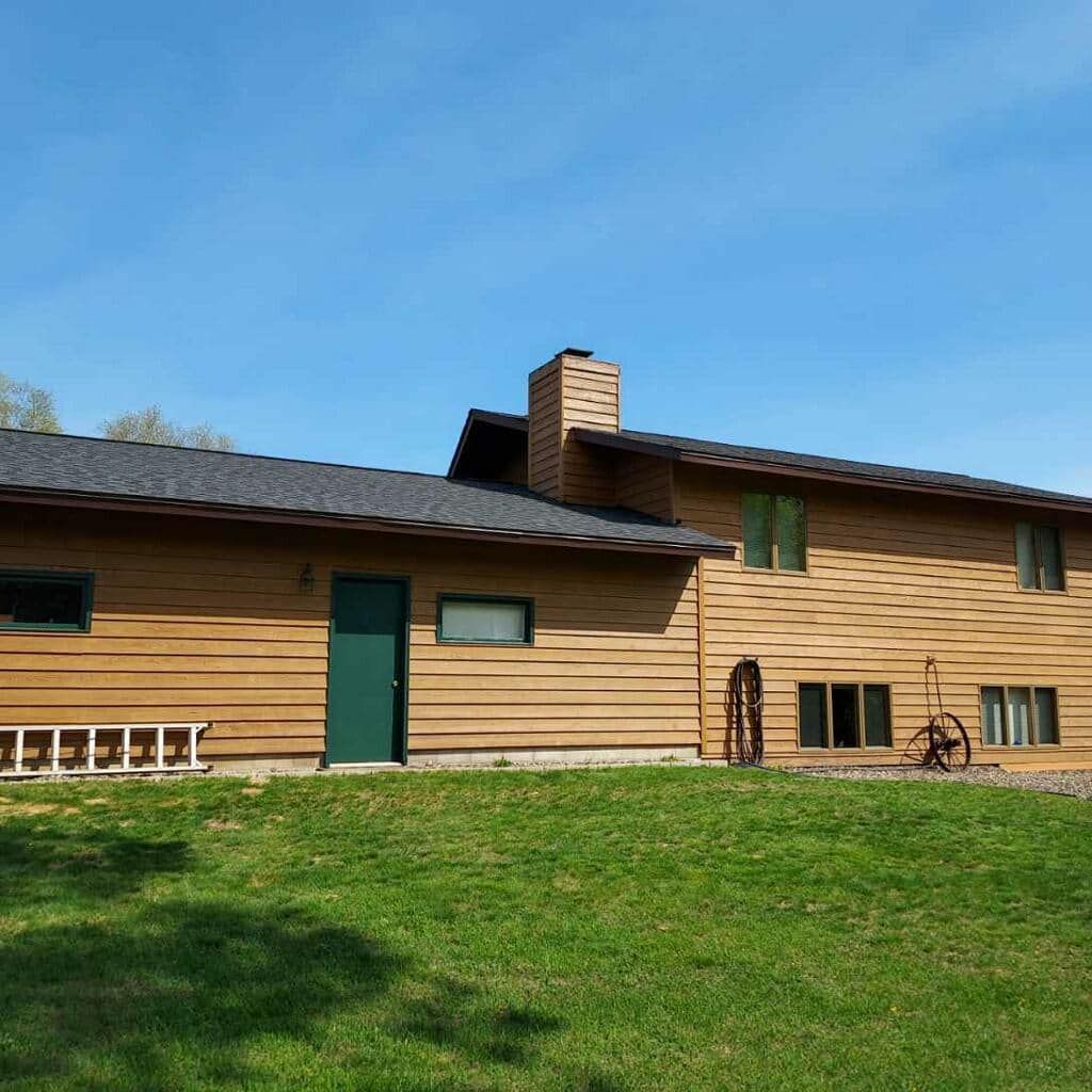 A large wooden house with a green door is sitting on top of a lush green field.