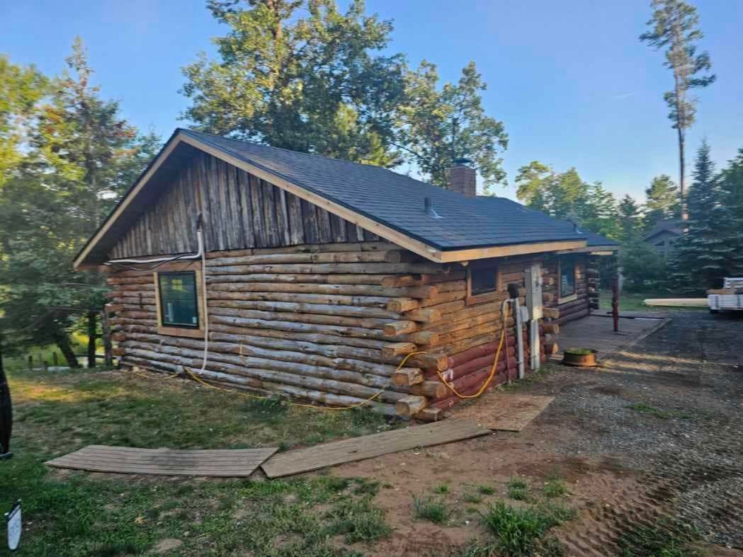 A small log cabin is sitting in the middle of a grassy field.