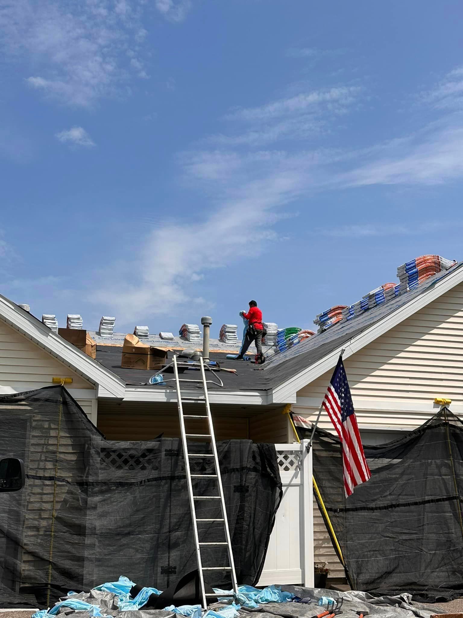 A man is standing on the roof of a house under construction.