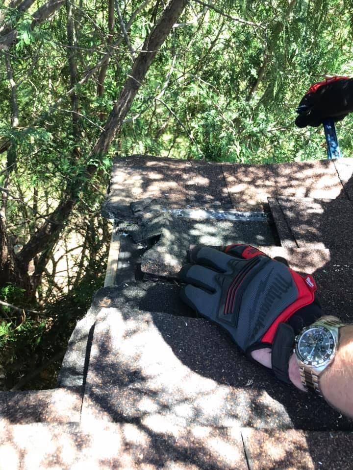 A person wearing gloves and a watch is working on a roof