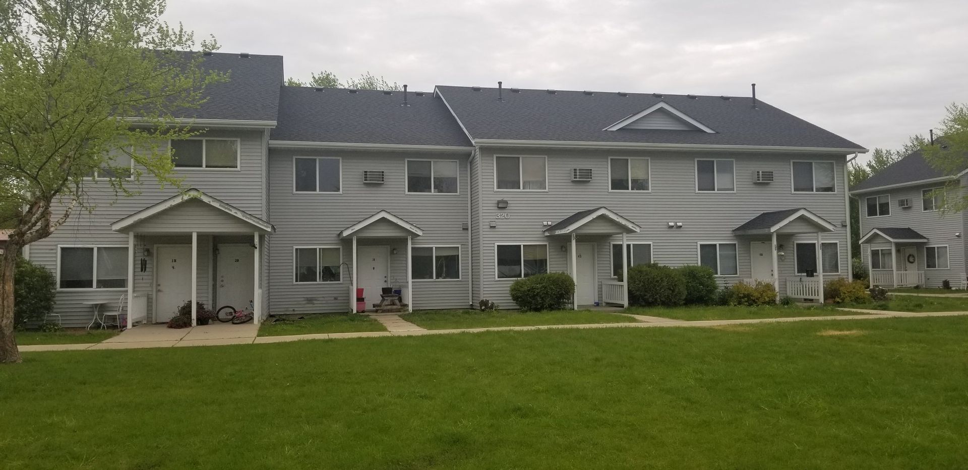 A row of apartment buildings with a lush green lawn in front of them