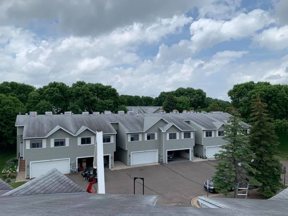 A row of houses with garages and trees in the background