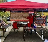 A man in a red shirt is standing under a red tent.