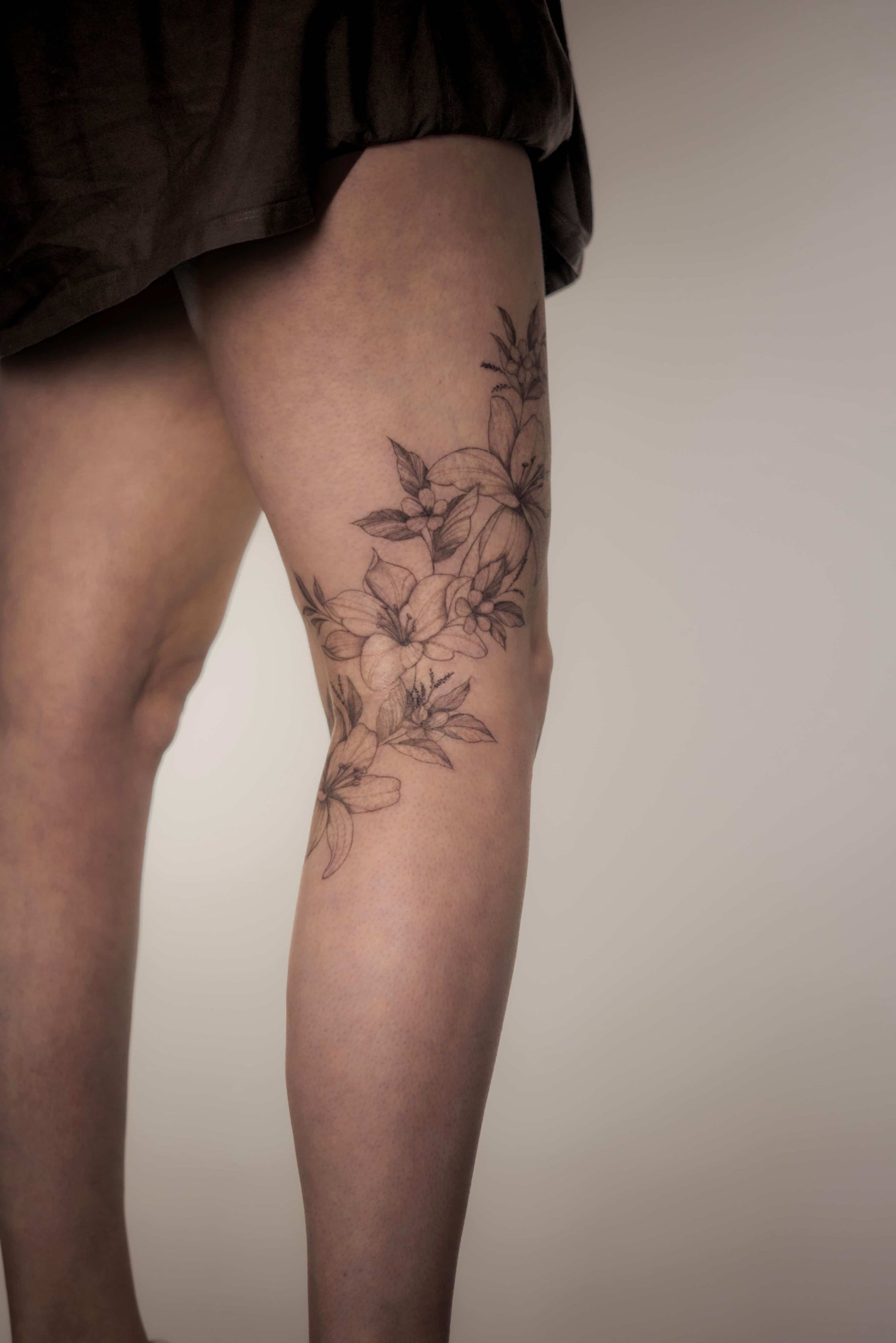 Leg with floral tattoo on the knee, brown garment visible above.