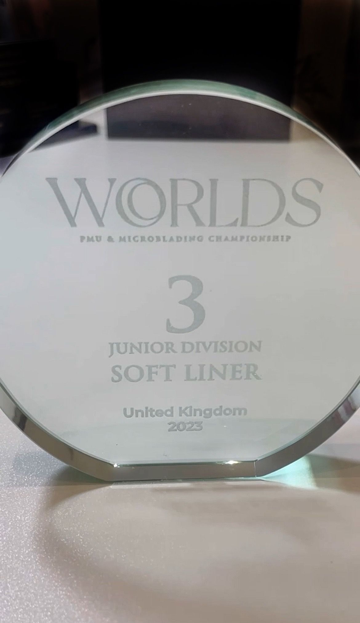 A glass plaque with the number 3 on it is sitting on a table.