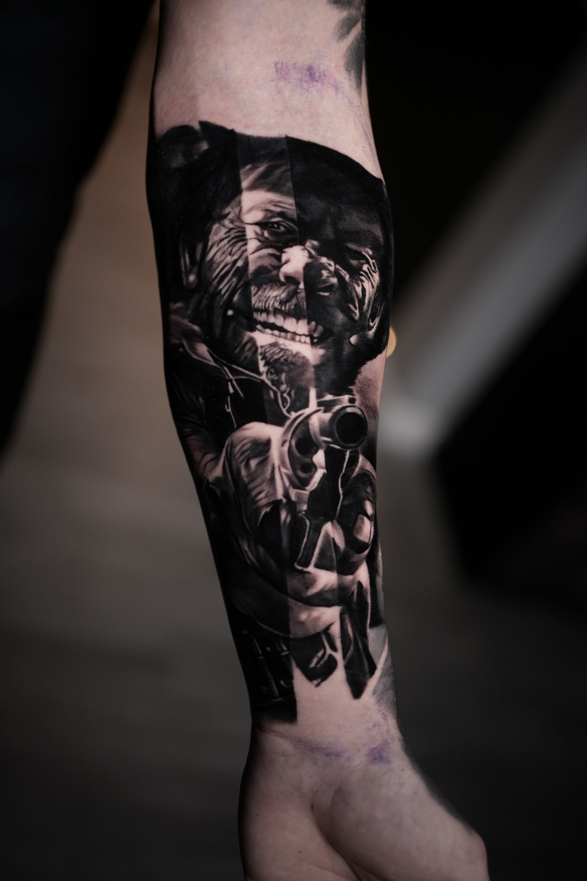 Tattoo of a person aiming a gun, forearm view, black and gray shading with segmented design.