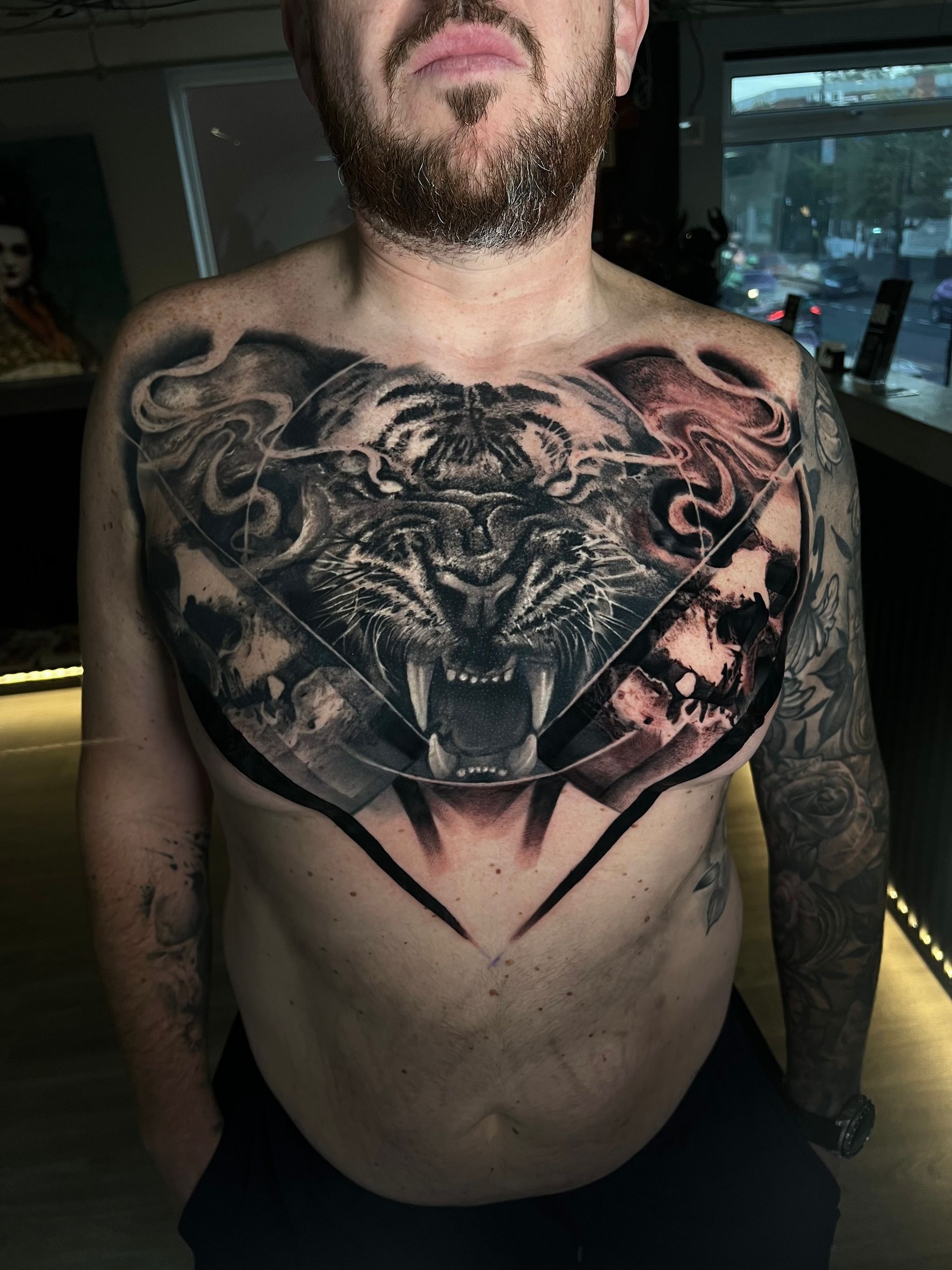 Man with chest tattoo of a tiger in a geometric design.