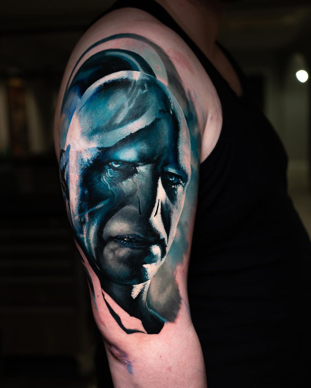 A man has a tattoo of a man 's face on his arm.