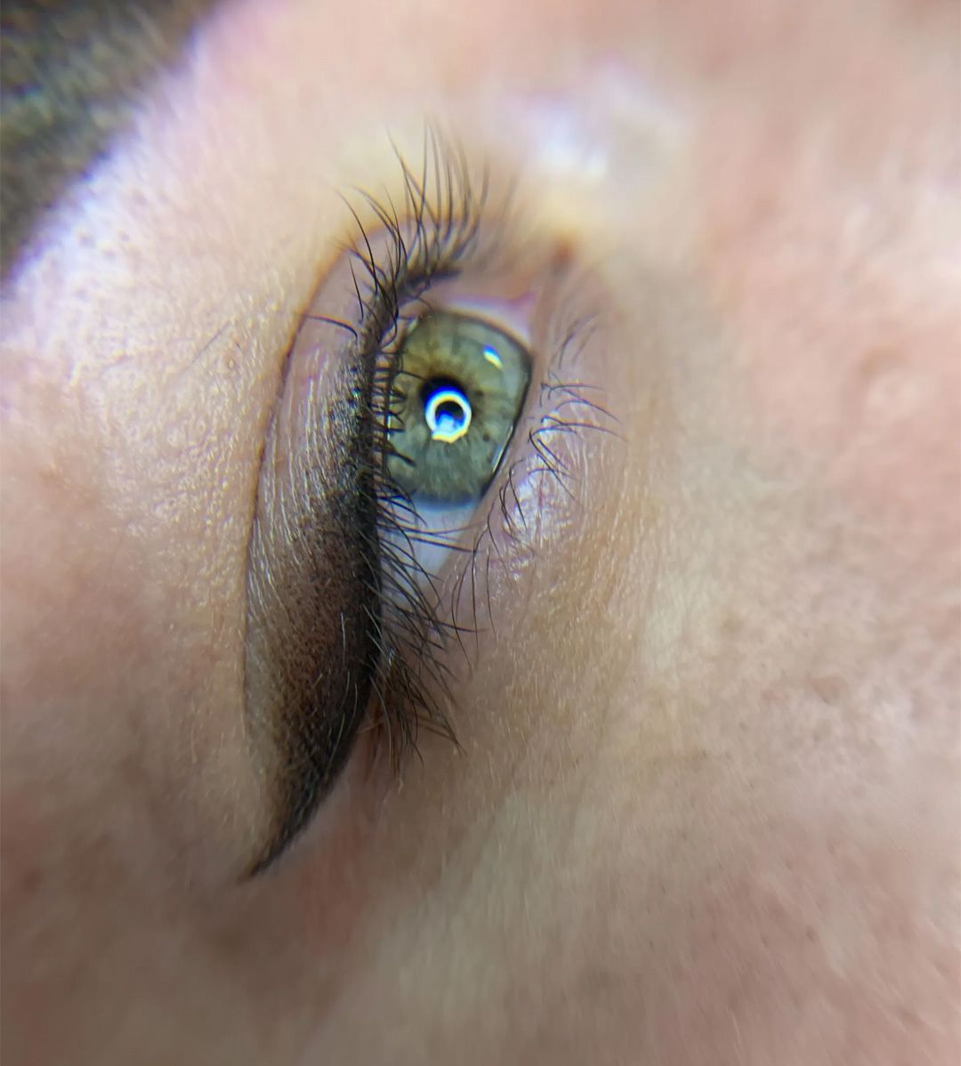 Close-up of a person's eye with eyeliner applied. The eye is green.