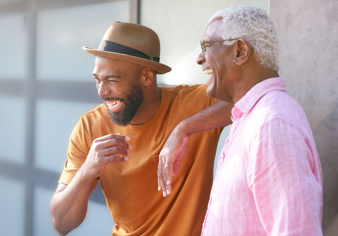 A man in a hat is standing next to an older man in a pink shirt.