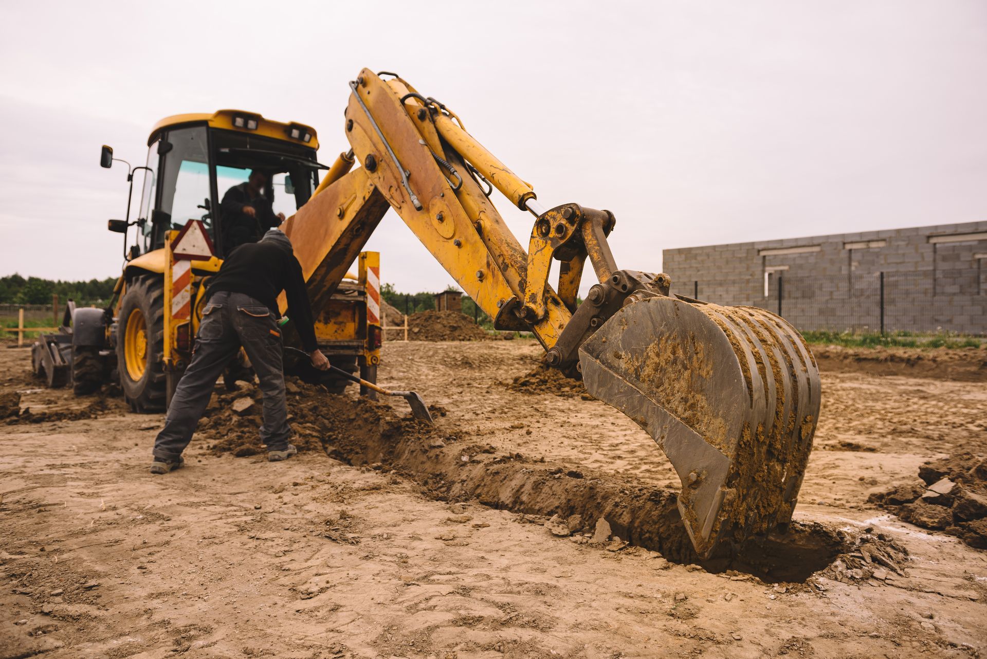 Excavator working at house construction site - digging foundations for modern house. Beginning of house building. Earth moving and foundation preparation.