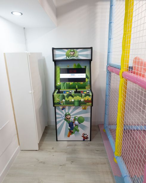 Máquina recreativa con gráficos deportivos verdes en una estrecha zona de juegos interior.
