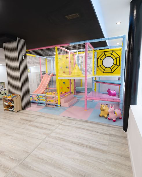 Parque de bolas para niños con redes para trepar, toboganes y bloques blandos sobre un suelo acolchado.