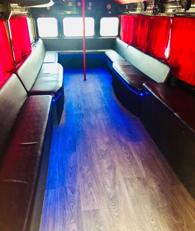 The inside of a bus with red curtains and blue lights.