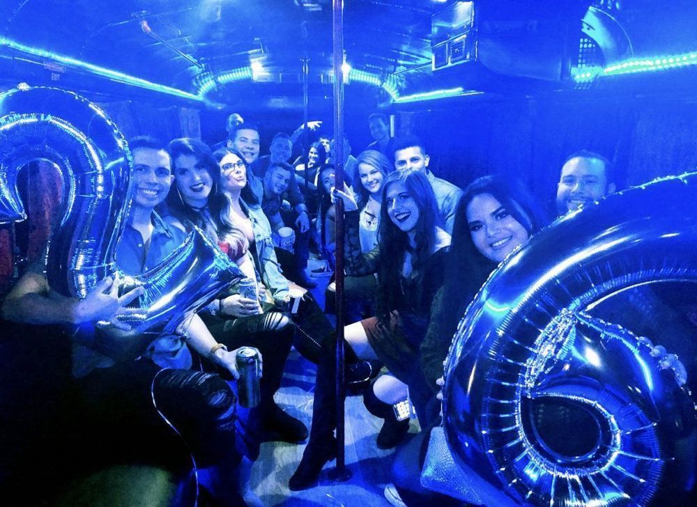 A group of people are sitting on a bus holding balloons.
