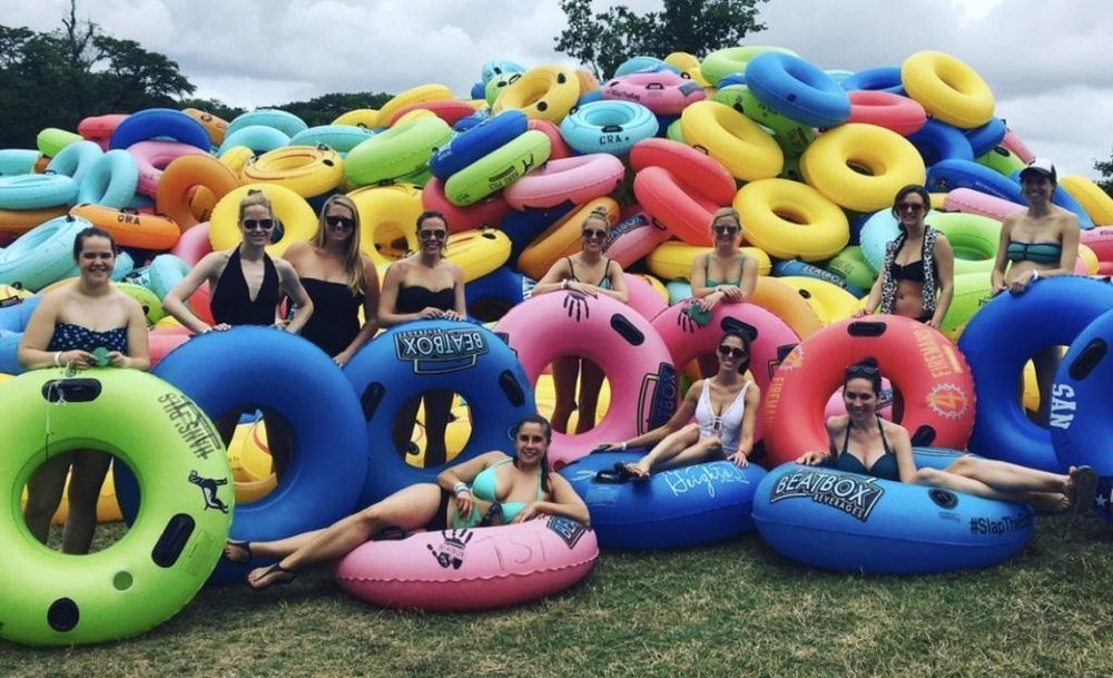 A group of women are sitting in a pile of inflatable tubes.