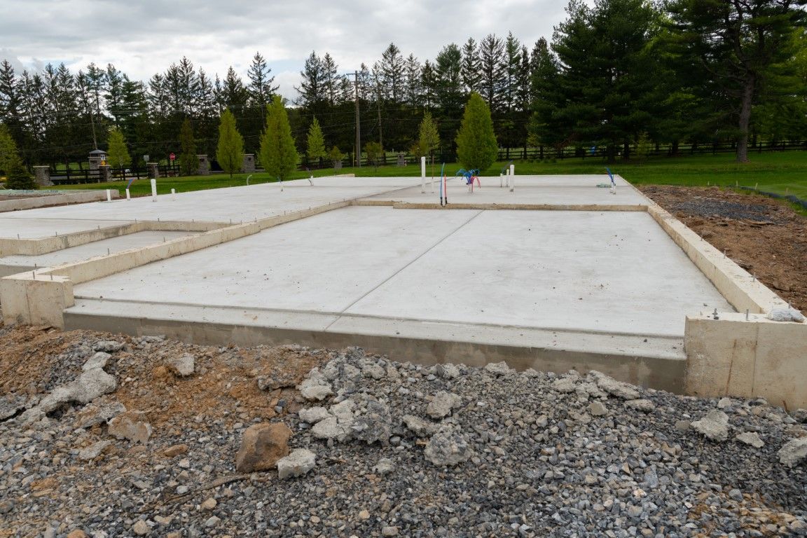 Workers pouring concrete over steel rebar for a foundation.