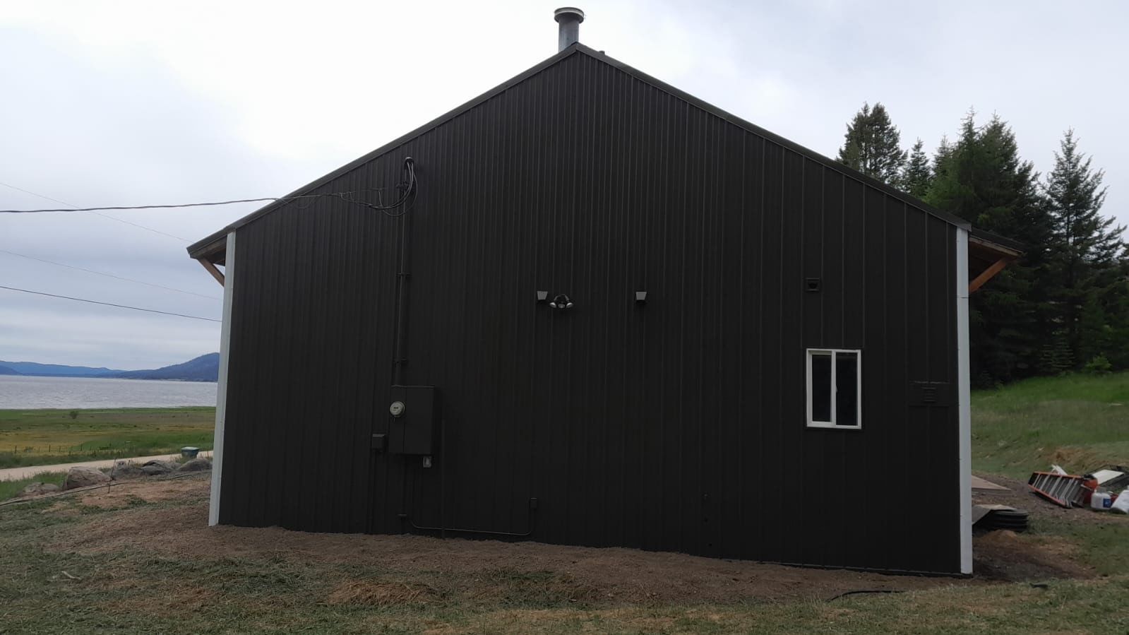 Dark wooden barn or shed beside a field under an overcast sky