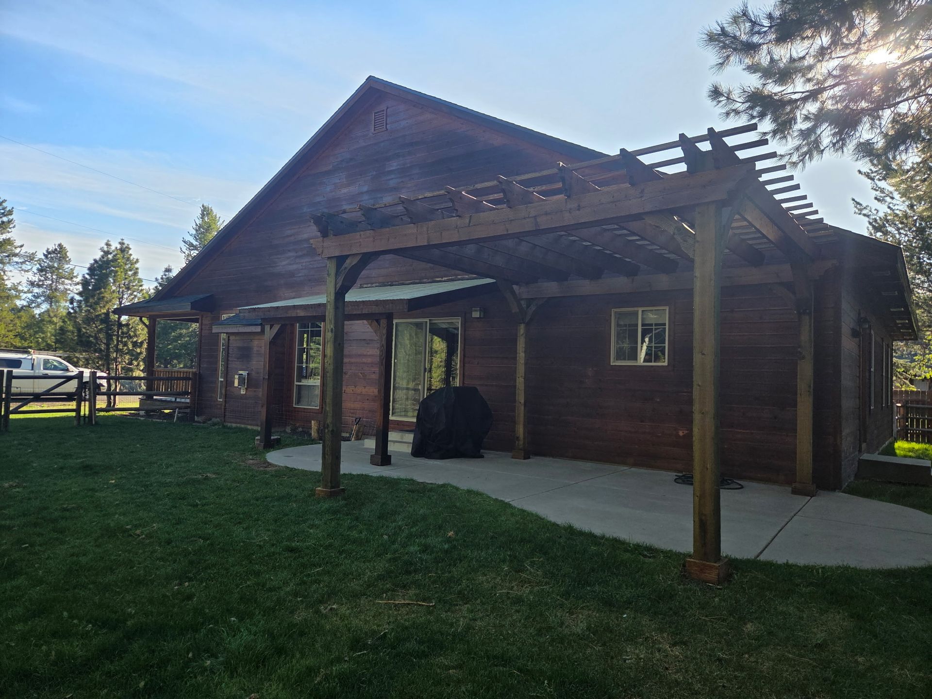 Rustic wooden cabin with a covered porch in a grassy yard under a clear sky