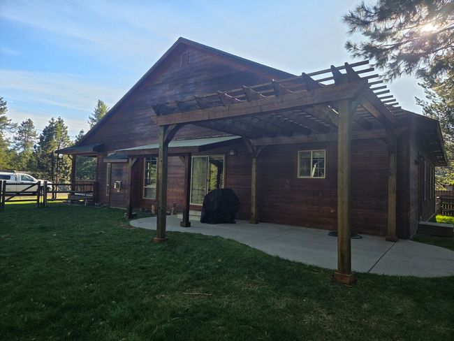 Rustic wooden cabin with covered porch and grassy yard in bright daylight