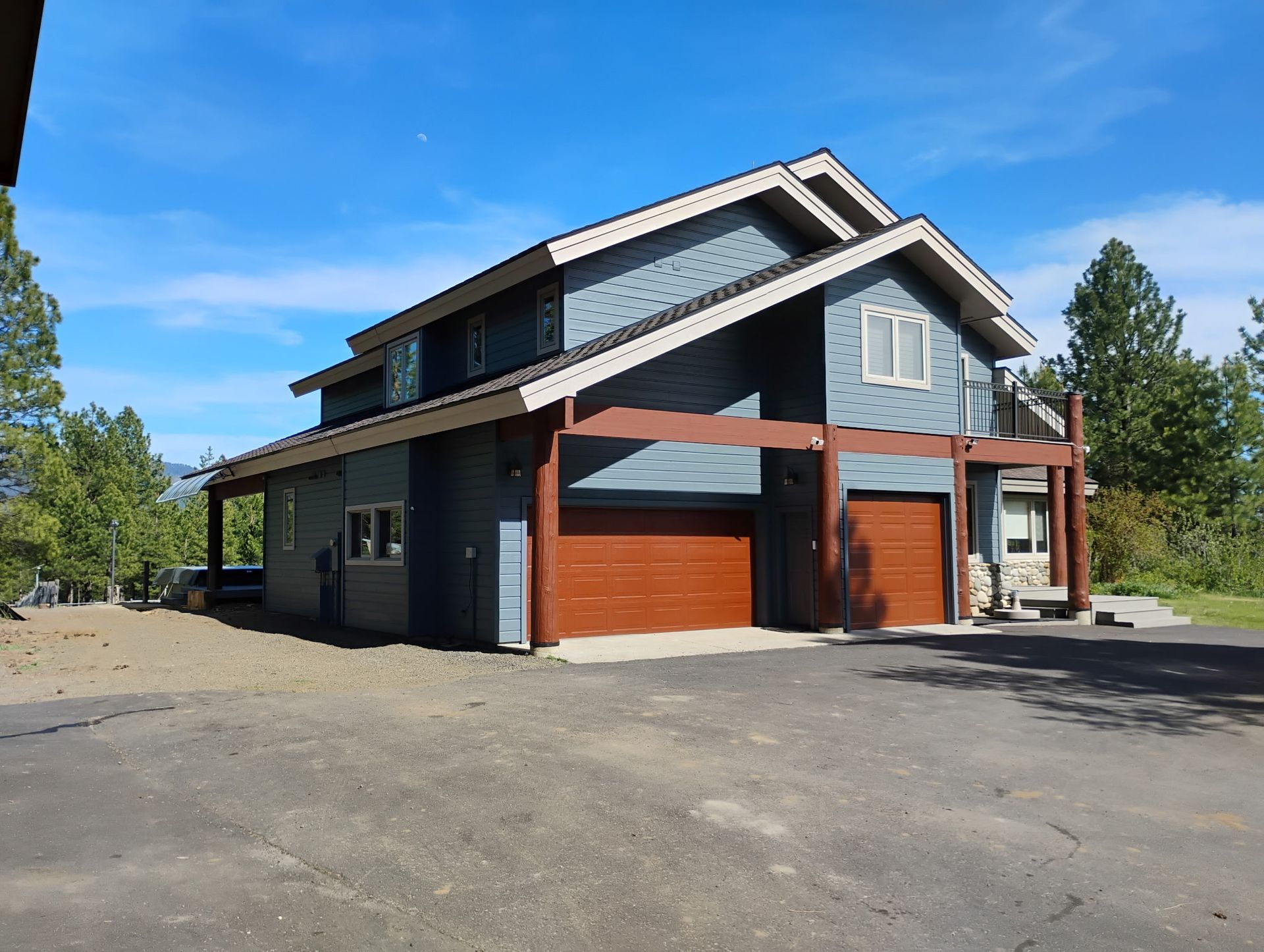 Modern two-story house with dark siding and red garage doors on a sunny day