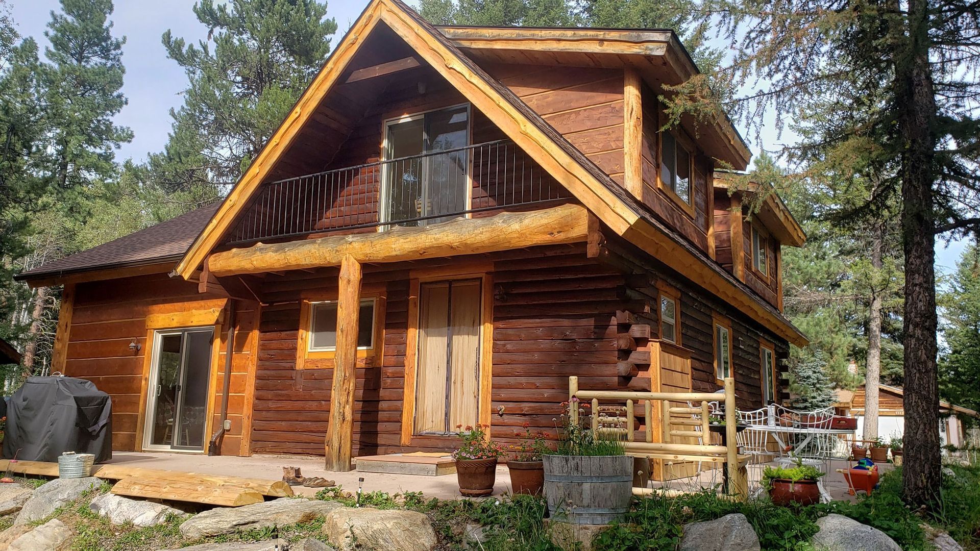 Rustic wooden cabin with a porch, stone accents, and trees in a wooded setting