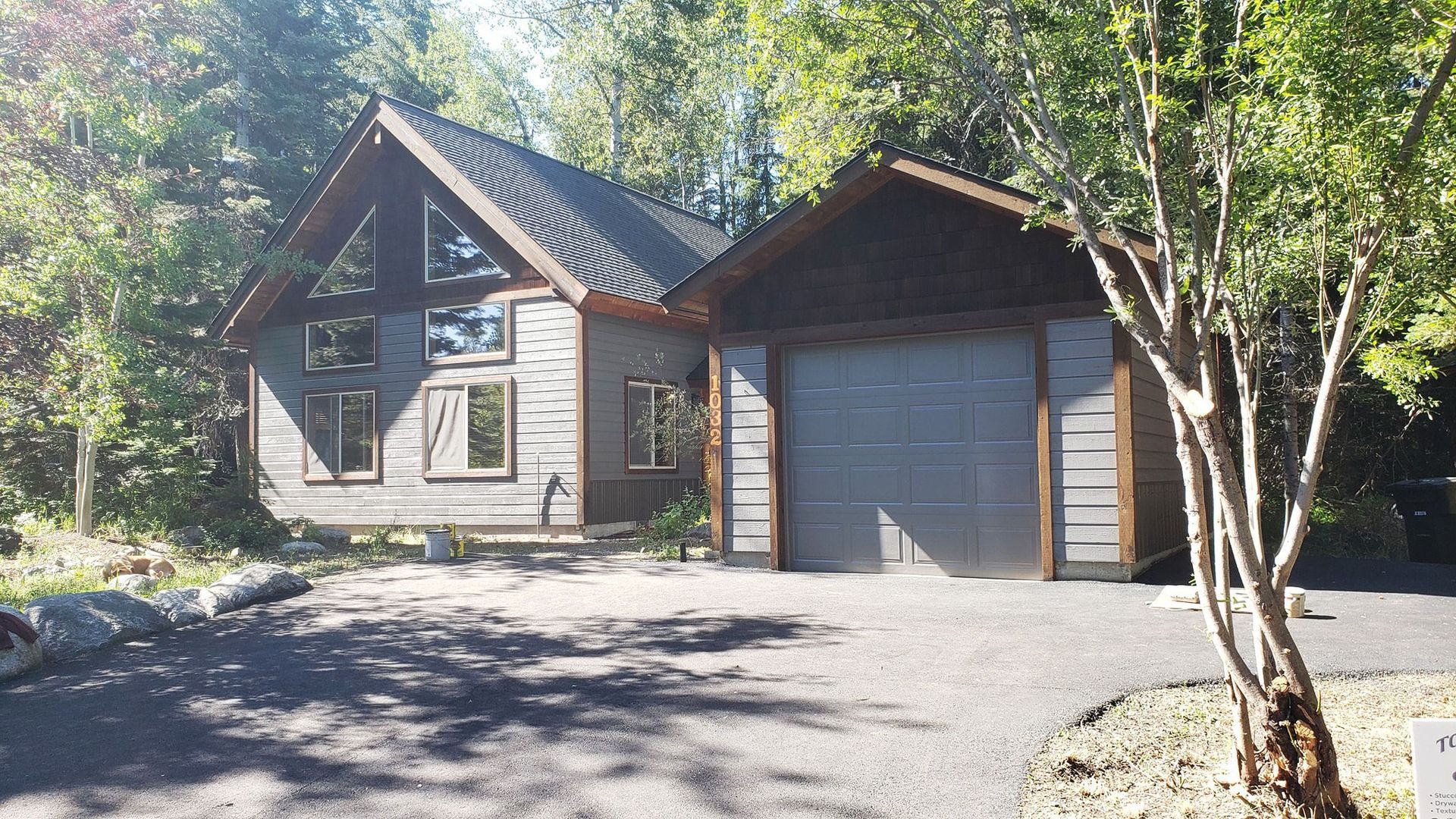 Wooden cabin with garage in a sunny wooded driveway