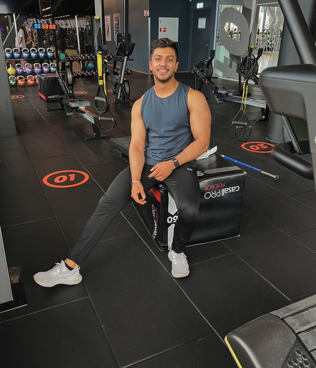 Kamal is sitting on a bench in a gym.