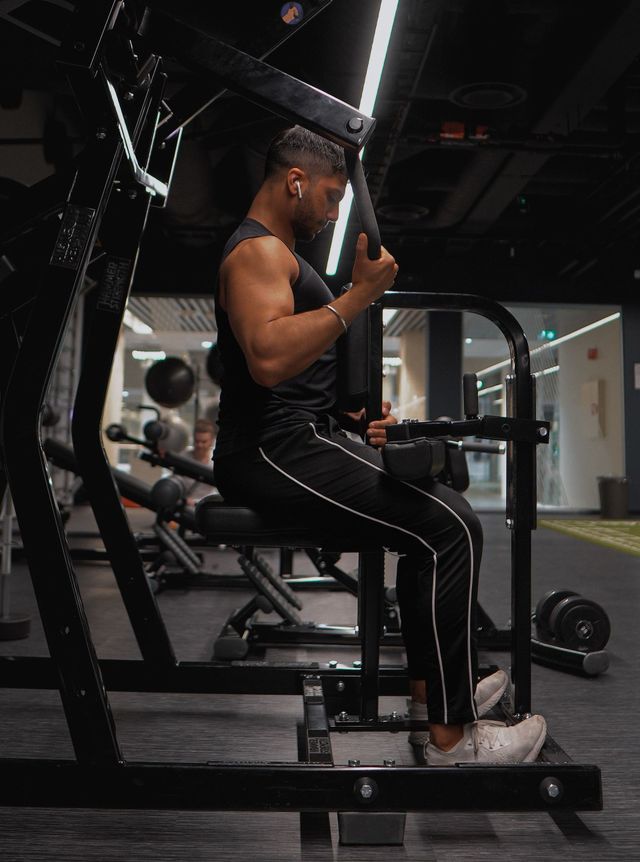 Kamal is sitting on a machine in a gym.
