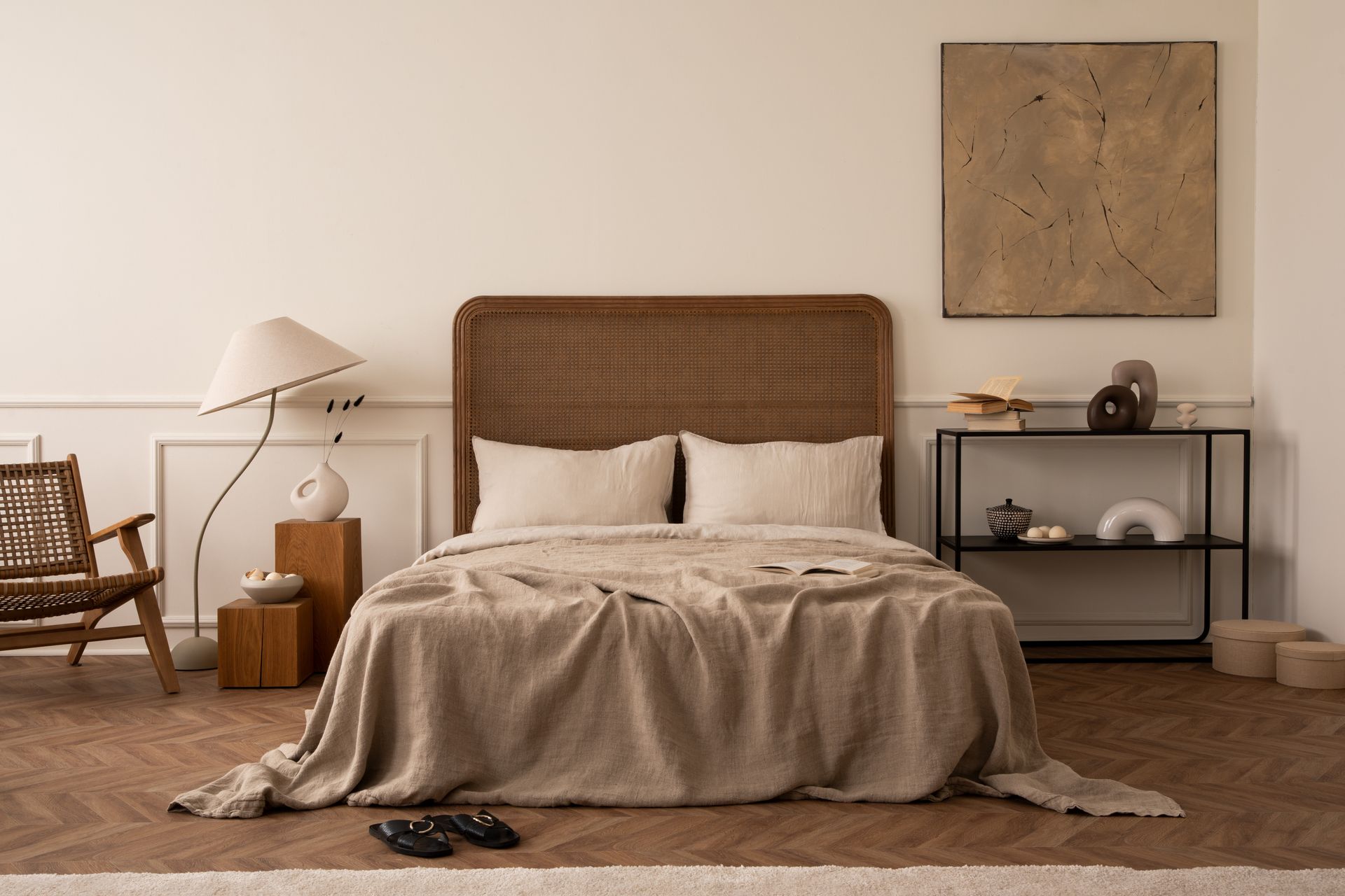 A bedroom with a bed , chair , nightstand , lamp and painting on the wall.