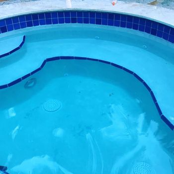 Blue swimming pool with curved tile edges and clear turquoise water