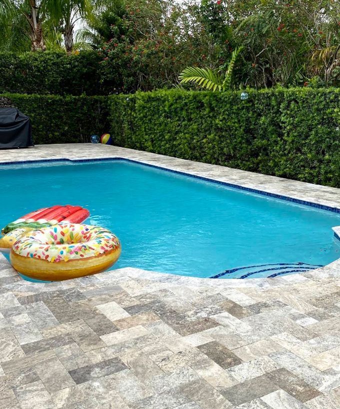 Backyard swimming pool with a colorful inflatable donut float and stone patio