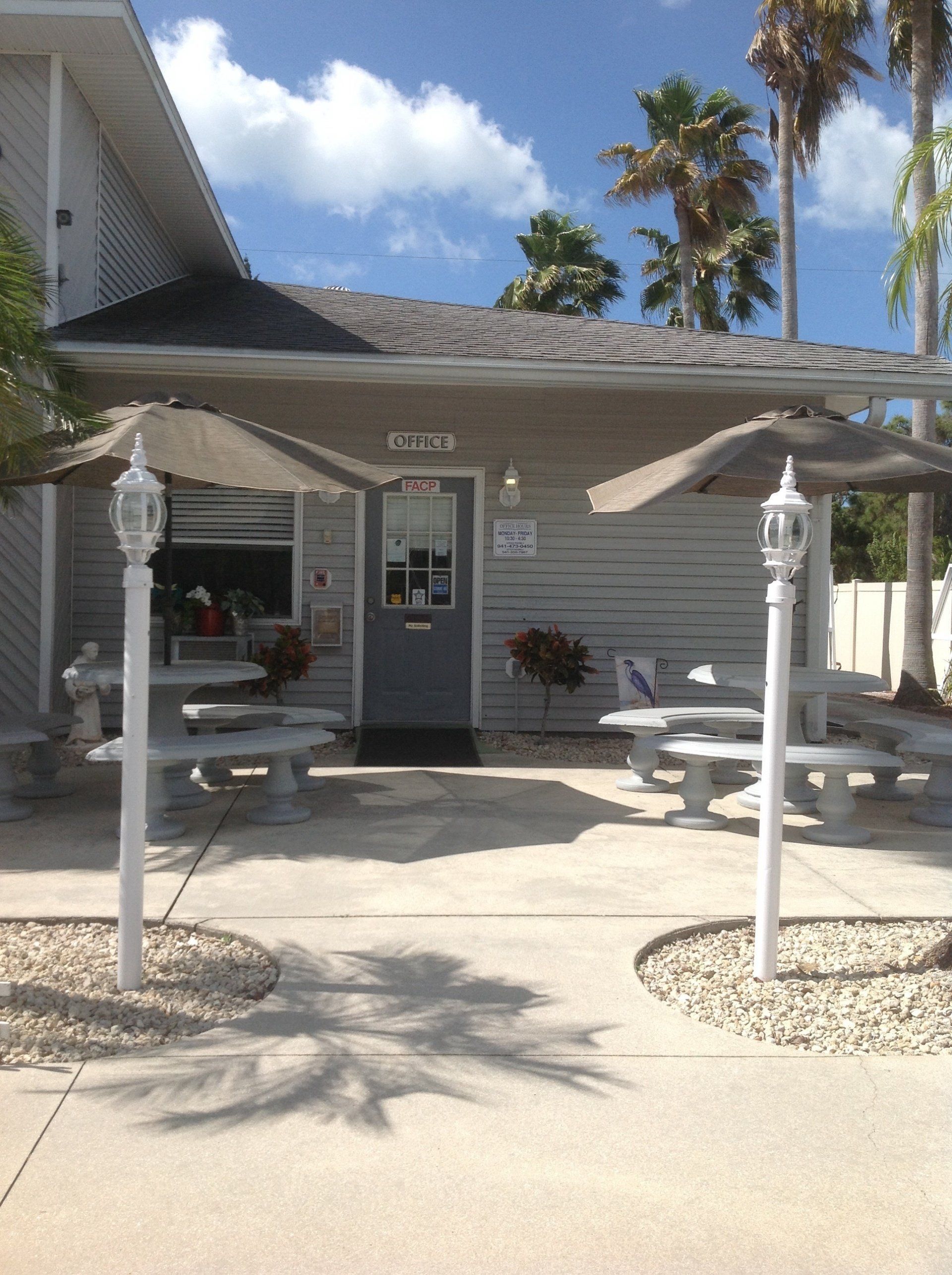 The Front Of A House With A Covered Porch And Umbrellas