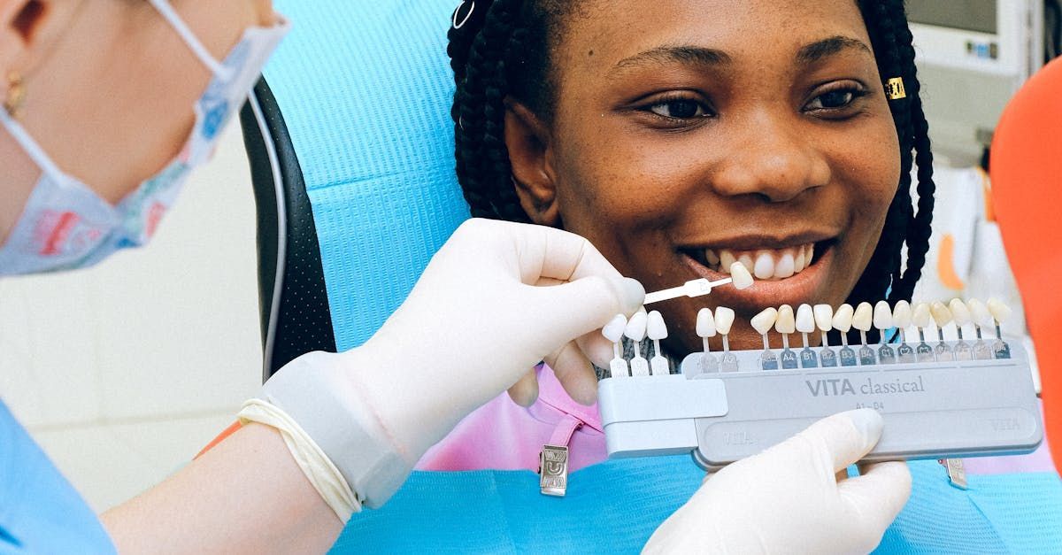 Dentist examining teeth with a shade guide while patient smiles in a dental clinic