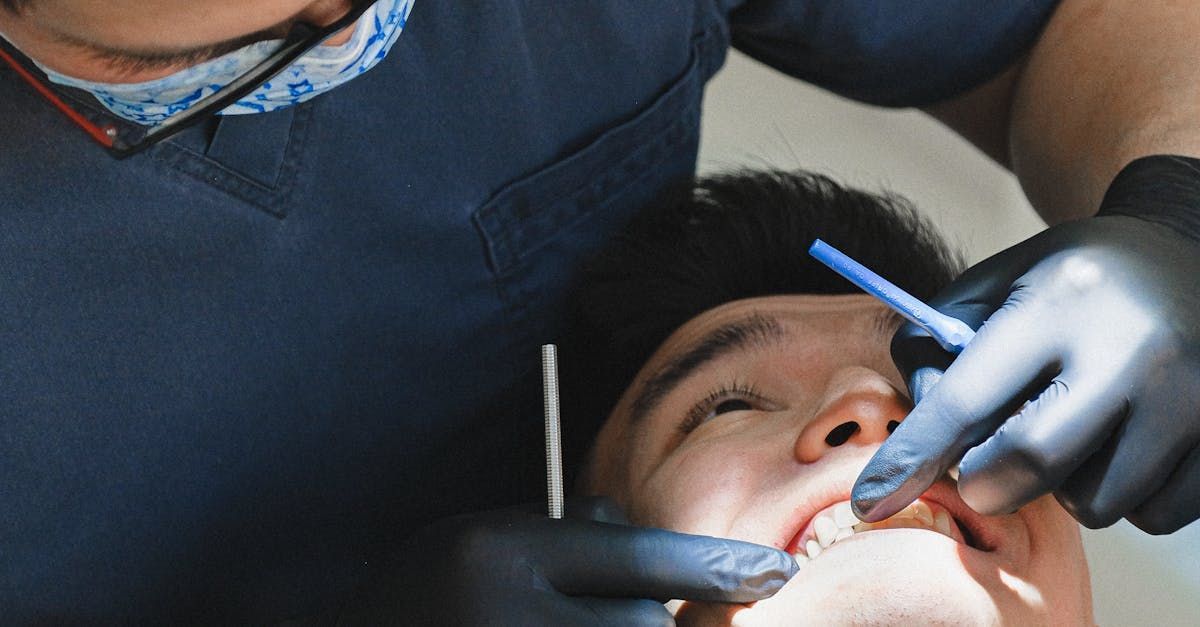 Dentist using a tool to treat a patient lying back in a chair, close-up inside the mouth
